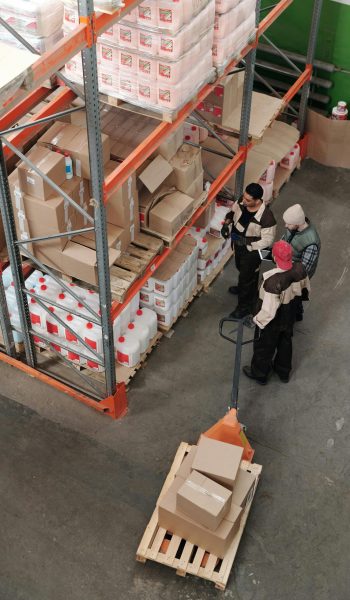 Three warehouse workers discussing inventory organization details.